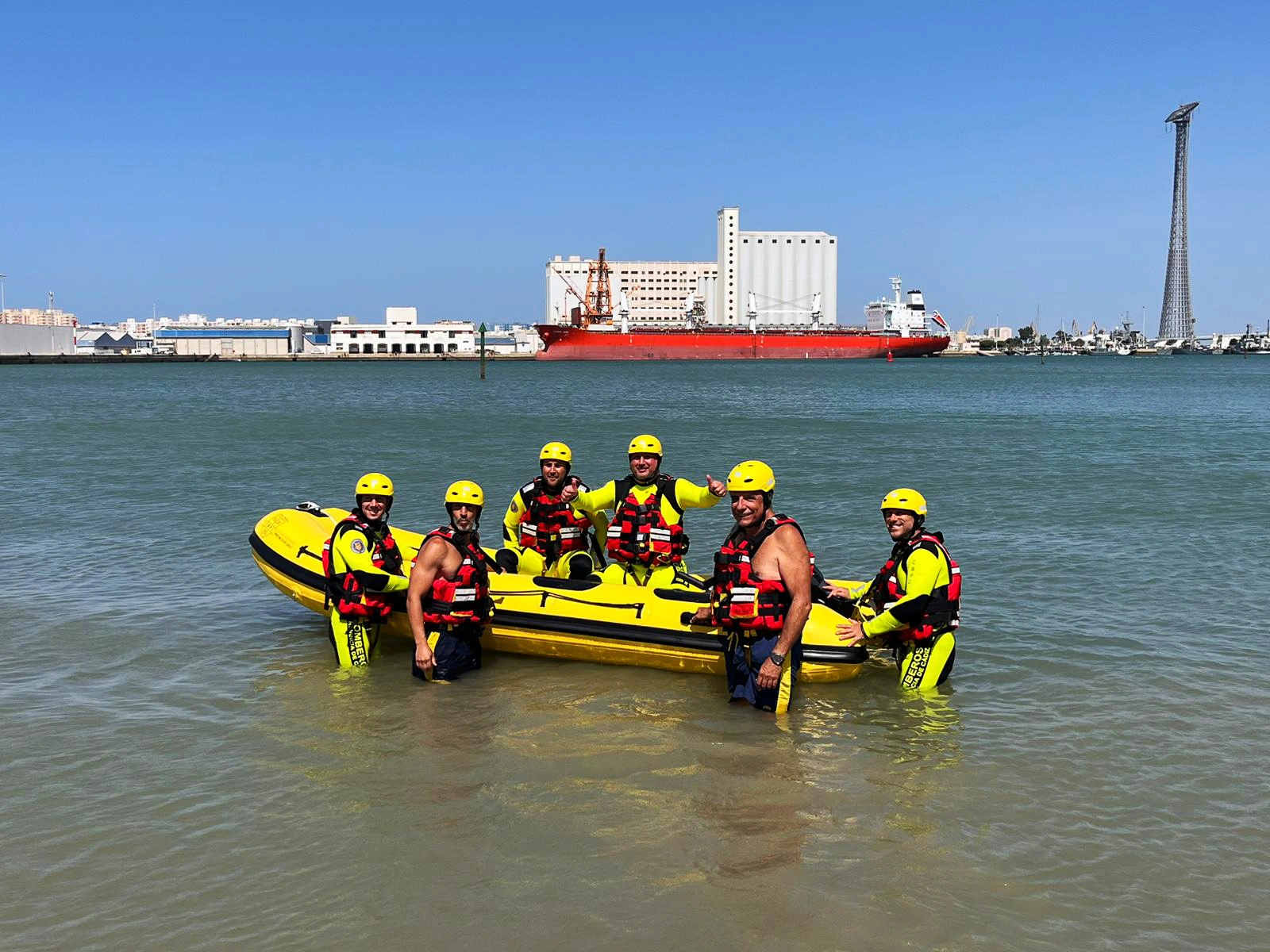 Bomberos en una playa junto a una embarcación tipo zodiac